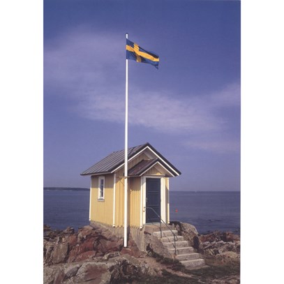 Gul stuga vid havet med flagga